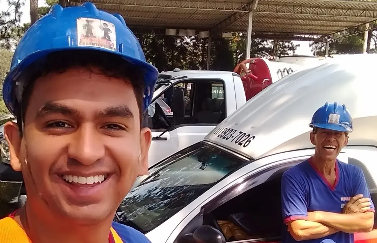 Dois técnicos da Suprema de capacete azul ao lado do caminhão de sucção